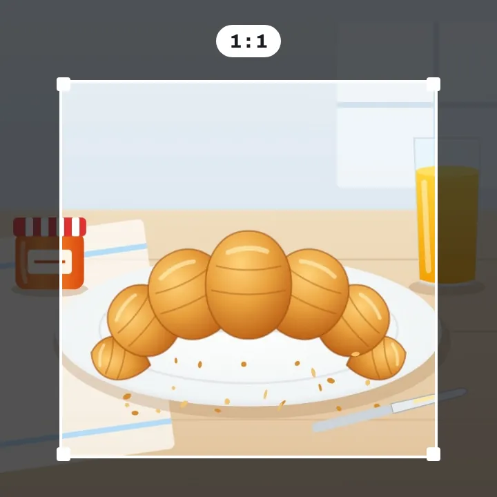 A croissant on a plate with a square crop frame drawn around it, the parts outside dimmed